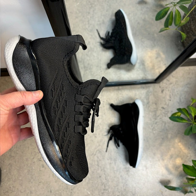 Sorte strikkede slip on sko med en fast kant i åbningen.
