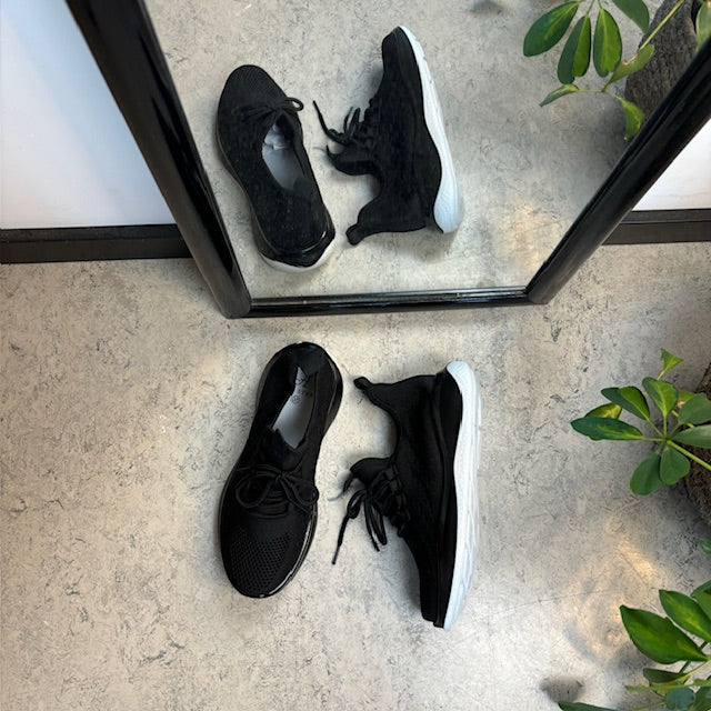 Sorte strikkede slip on sko med en fast kant i åbningen.